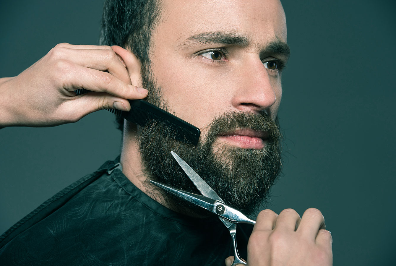 O barbeiro profissional está estilizando a barba do cliente.