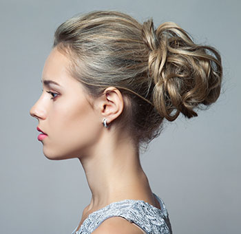 Retrato lateral de una clienta mostrando su nuevo peinado después de reservar un servicio de peluquería utilizando la aplicación Planfy.com.