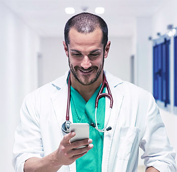 Doctor de sexo masculino que controla su horario de citas en un teléfono inteligente.