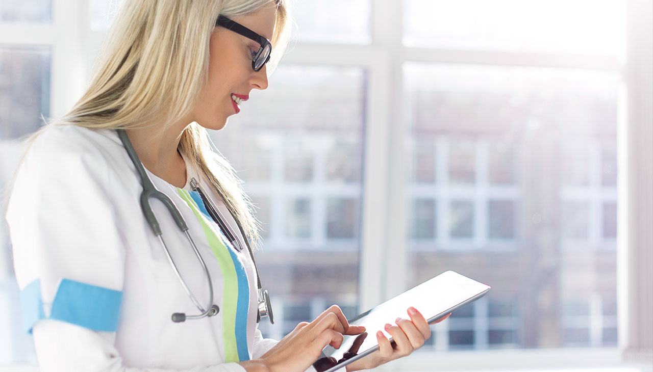 Женщина-врач управляет онлайн-бронированием с помощью системы бронирования Planfy на своем планшете.