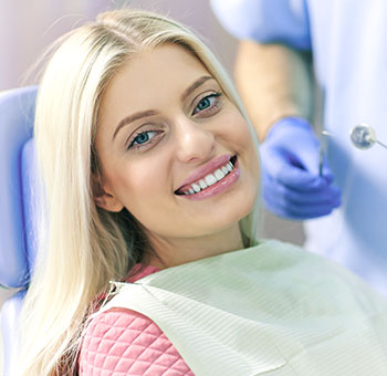 Paziente della donna che sorride nella poltrona del dentista dopo un trattamento di sbiancamento dei denti.