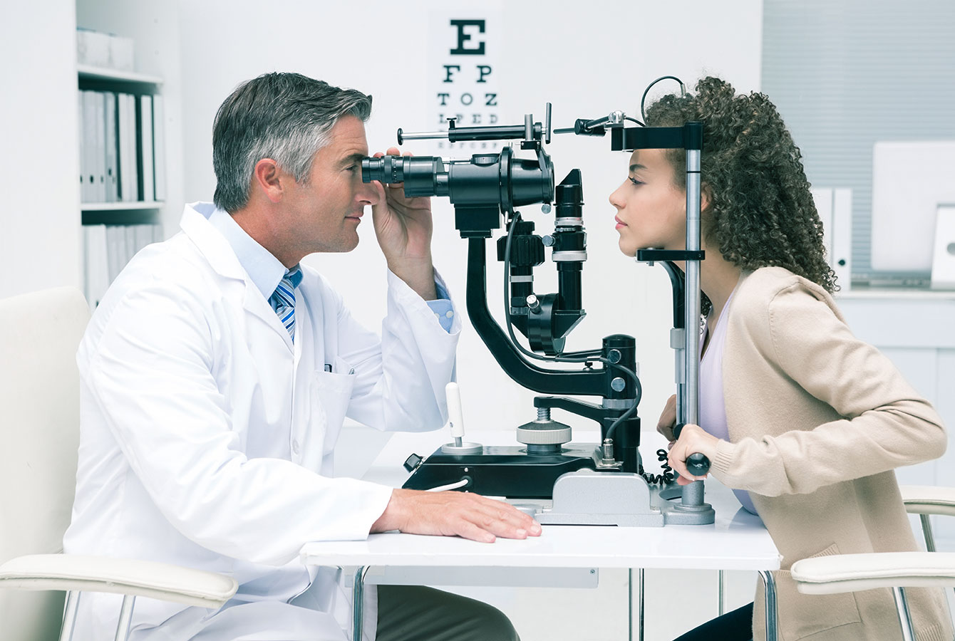 Офтальмолог проверяет глаза пациентки в окулисте.
